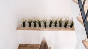 Eine Treppe mit hölzernem Geländer, eine Holzplattform mit Pflanzen und eine weiße Wand.