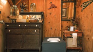 Une salle de bain en bois avec un lavabo ancien, un miroir et des toilettes.