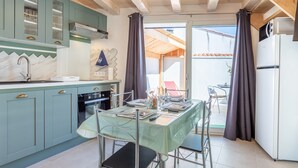 Una cucina con tavolo, sedie, pensili e frigorifero.