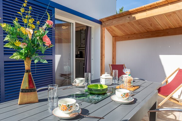 Una mesa de comedor dispuesta con cristalería, platos y un jarrón con flores.