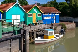 Un hilera de casas coloridas junto a un río tranquilo, un muelle y un pequeño bote.