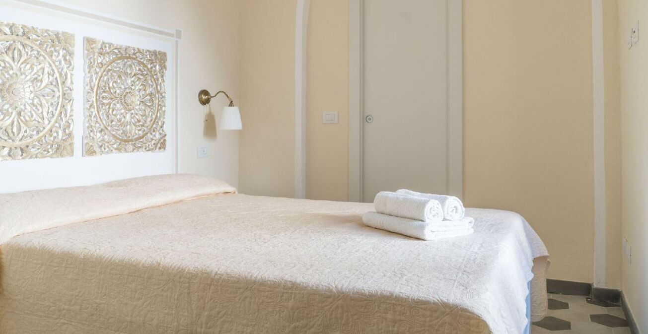A neatly made bed with a white bedspread and a folded towel on the side.