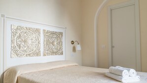 Habitación de hotel con cama, paneles decorativos en la pared, lámpara de noche y una puerta.