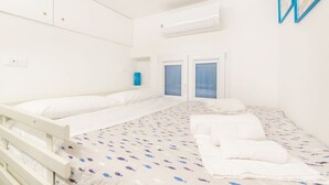 A room with a bed, a window, and a wall-mounted air conditioner.