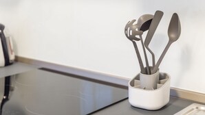 A kitchen counter with a modern induction cooktop and a utensil holder with various kitchen tools.
