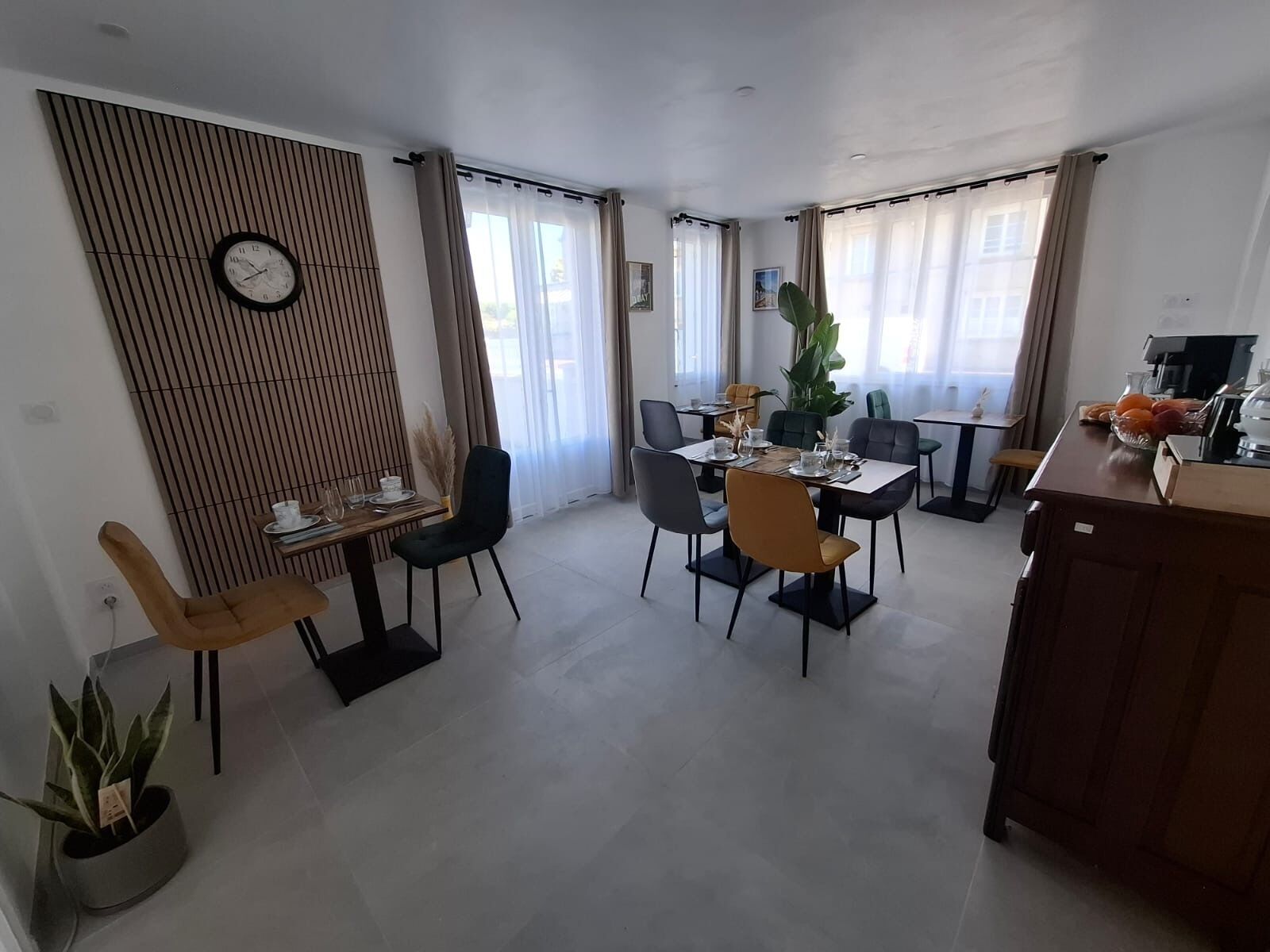 A modern dining area with a wooden partition, a dining table set for four, and a kitchen area with a coffee machine.