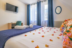 A hotel room with a bed, a TV mounted on the wall, a desk with a chair, and a window with curtains. - Luxury Detached House   (Montebourg)