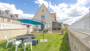 A backyard with a table and chairs, a blue umbrella, and a white fence. - Luxury detached house (Montebourg)