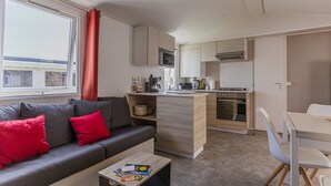 Un espace de vie compact comprenant un canapé, une petite table basse, une kitchenette et un coin repas.