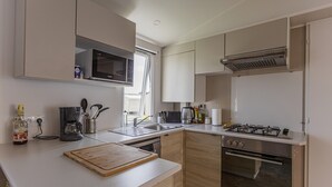 Une cuisine moderne équipée d’un four à micro-ondes, d’une cuisinière, d’un four et d’une planche à découper en bois posée sur le plan de travail.