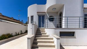 A modern building with a white exterior, a set of stairs leading to a door, and a small window on the side. - Villa 'Primavera' with sea view, private terrace and air conditioning (Marina di Modica)