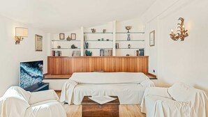 Une chambre d’hôtel avec un mur lambrissé en bois, un canapé-lit, une table basse et une bibliothèque agrémentée d’objets décoratifs.