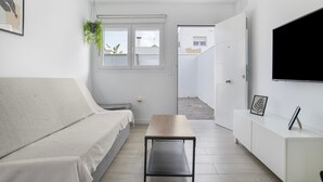 Une chambre moderne et minimaliste, dotée d’un lit, d’une petite table, d’un téléviseur et d’une fenêtre offrant une vue agréable.