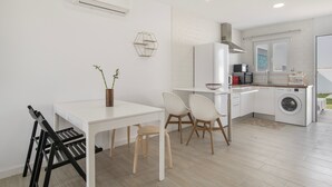 Une cuisine moderne équipée d’un lave-linge, un coin repas avec une table et des chaises, et une petite plante posée sur la table.