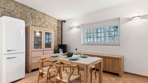 Una cucina con parete in pietra, frigorifero bianco, mobili in legno e tavolo da pranzo per quattro persone.