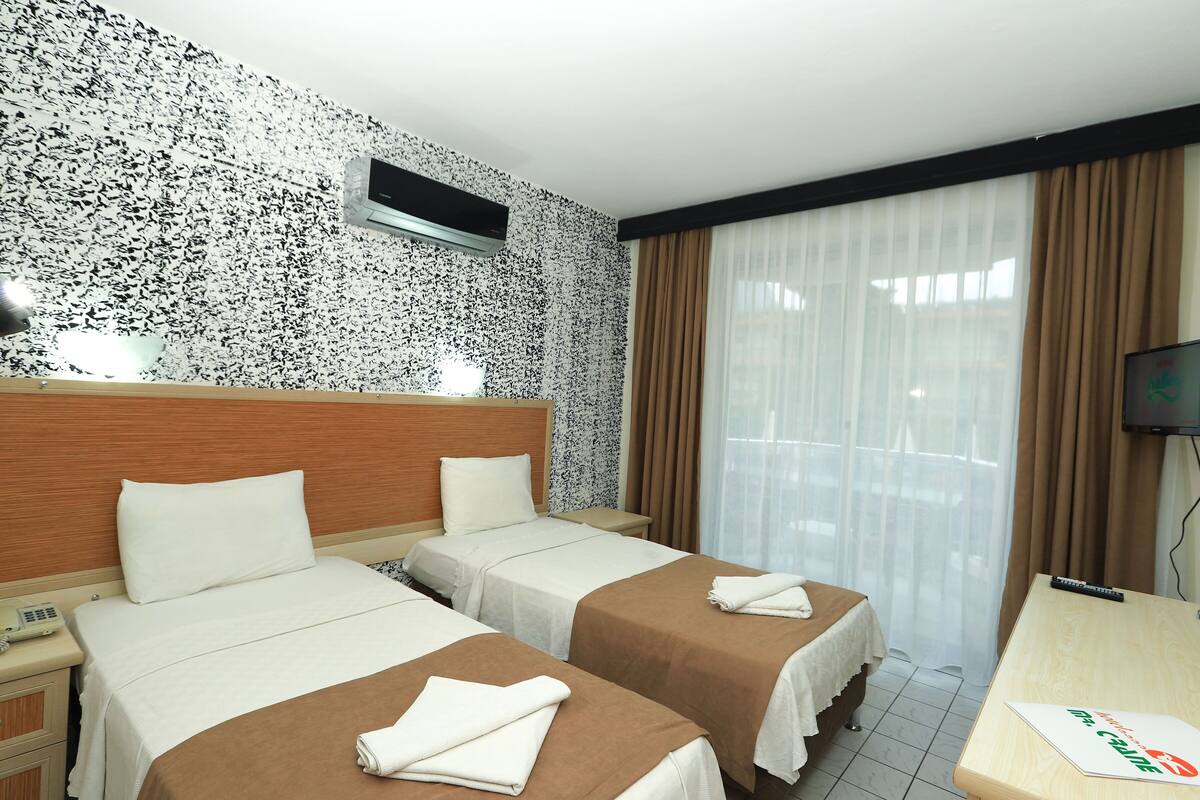 Une chambre d’hôtel avec deux lits, un bureau, une télévision et une fenêtre avec des rideaux.