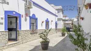 Une rue étroite bordée de bâtiments blancs, de portes bleues et de murs en pierre.