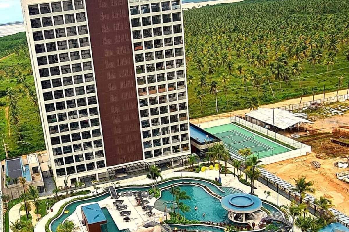 Un resort con varias piscinas, parque acuático y un edificio grande de diseño moderno.