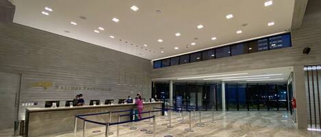 A spacious lobby with a reception desk, a second-floor balcony, and a modern design.