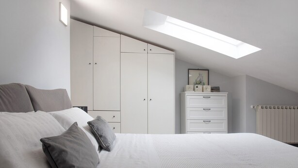 Une chambre à coucher avec un lit, une armoire, une commode et une lucarne.