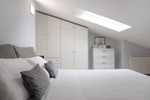 A bedroom with a bed, a wardrobe, a dresser, and a skylight.