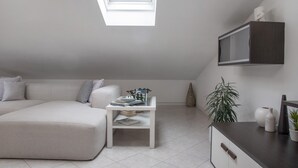 Une chambre de style loft moderne, dotée d’une lucarne, d’un canapé blanc, d’une petite table blanche et d’un bureau en bois foncé.