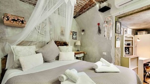 A bedroom with a bed, white bedding, a wooden headboard, a bedside table with a lamp, and a wall clock. - My Home, Welcome Way (Riomaggiore)