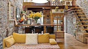 A cozy living room with a sofa, a dining area, and a staircase. - My Home, Welcome Way (Riomaggiore)