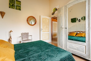 Een kamer met een bed, een stoel, een kledingkast en een spiegel.