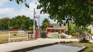 Un écurie abritant un cheval, un drapeau et un bâtiment traditionnel doté d’un toit rouge.