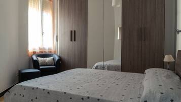 A bedroom with a bed, a chair, a wardrobe, and a bedside table.