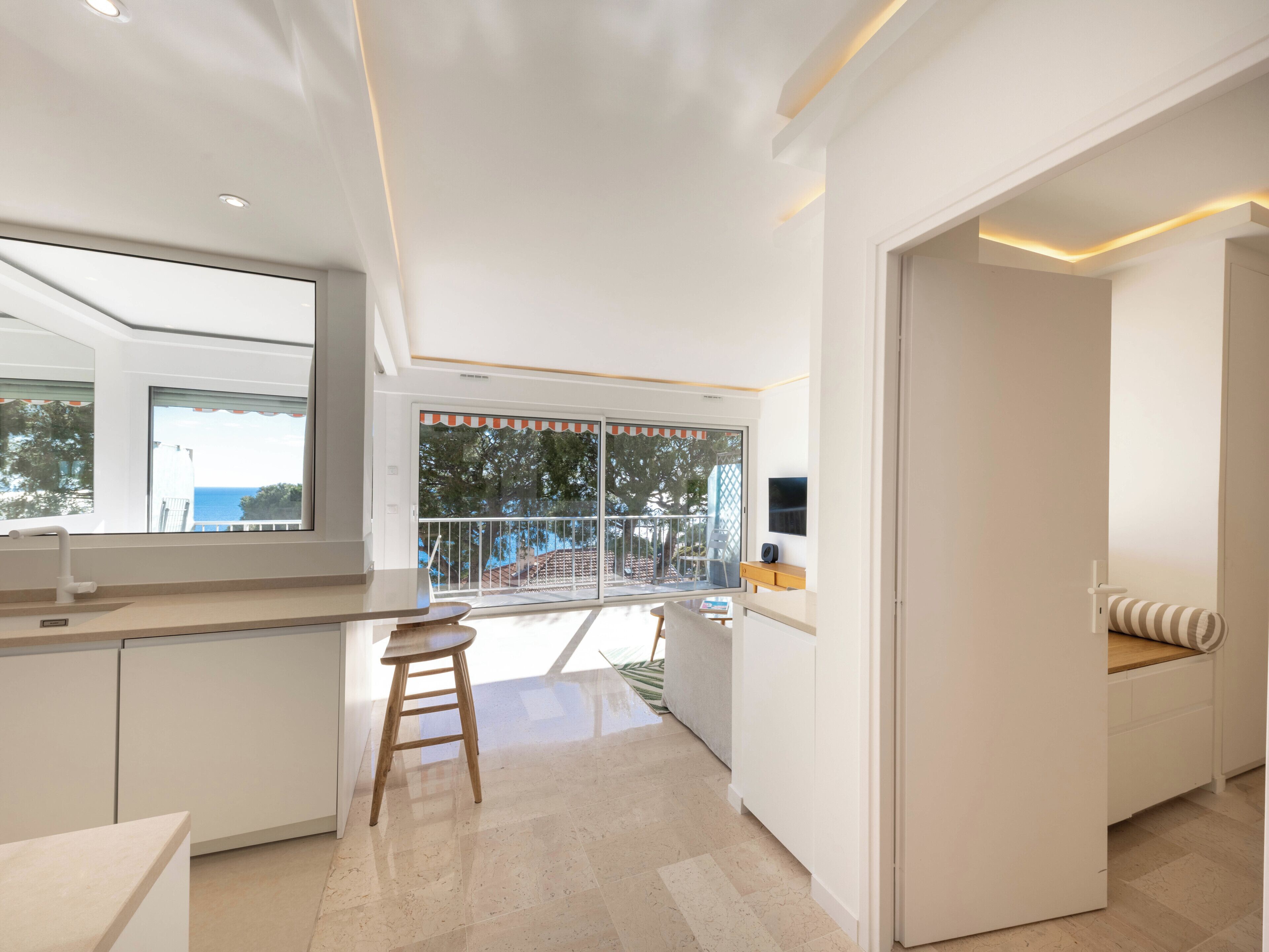 Et moderne køkken med et stort vindue, et spiseområde med høj stol og en balkon med udsigt.