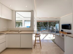 Uma cozinha moderna com uma janela grande, uma área de refeições com uma TV e uma varanda com vista.