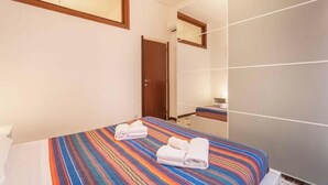 A hotel room with a bed, a bathroom mirror, and a door.