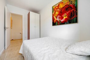 Ein Schlafzimmer mit einem Bett, einer Tür und einem Blumenbild an der Wand.