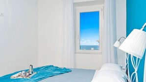 A bedroom with a bed, a window with a view of the sea, a bedside lamp, and a tray with a coffee pot and a book. - Queen of Sea Diamond, Terre Marine (Manarola)