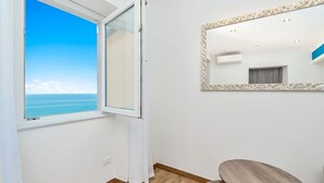 A room with a large window offering a view of the sea, a mirror with an ornate frame, and a round wooden table. - Queen of Sea Diamond, Terre Marine (Manarola)