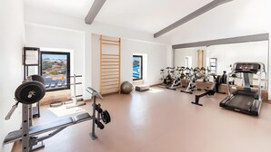 A gym with weightlifting equipment, cardio machines, and a view of a cityscape.