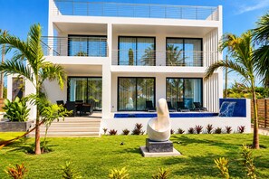 Een modern herenhuis met zwembad, terras en tropische beplanting.