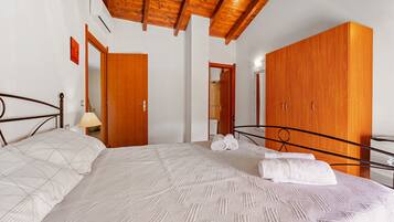 Une chambre à coucher avec un lit, une armoire en bois et un plafond avec des poutres apparentes.