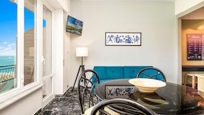 Un salon moderne avec un canapé bleu, une table ronde sur laquelle se trouve un bol, un lampadaire et un tableau accroché au mur.