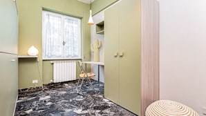 Une cuisine de taille réduite, avec un radiateur, une fenêtre avec des rideaux, une chaise et une petite table.