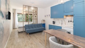 A modern kitchen with blue cabinets, a wooden dining table, and a blue sofa.