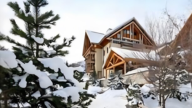 A large wooden lodge with multiple balconies, surrounded by snow-covered trees.
