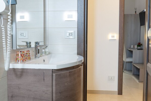 Une salle de bain moderne avec un grand miroir, un lavabo blanc et un meuble-lavabo en bois.