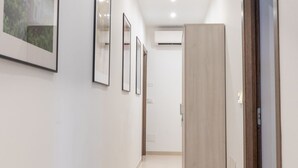 A hallway with framed pictures on the wall, a wooden wardrobe, and an air conditioning unit on the wall.