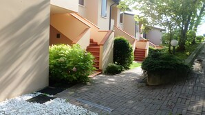 Un immeuble résidentiel doté d’un chemin pavé, d’un escalier et d’espaces verts.