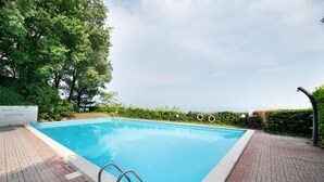 Une piscine rectangulaire avec un escalier en métal, entourée d’une terrasse en briques.