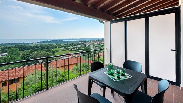 Un balcon avec une table et des chaises, une vue sur un paysage et un plafond en bois.