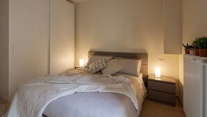 Un dormitori amb llit, fallegueres, armari i radiador.